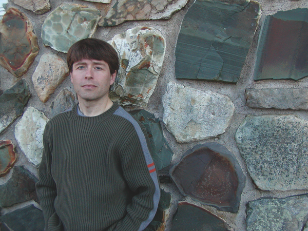 A man stands against a stone wall