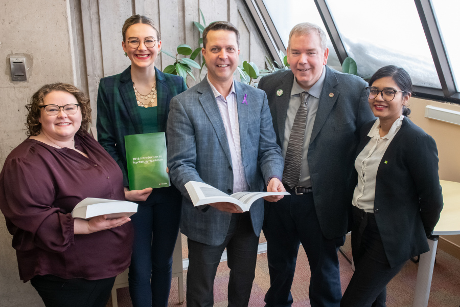 Five smiling people in a library