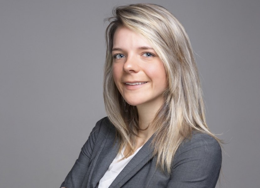 A portrait of a smiling young woman with long hair and a grey suit