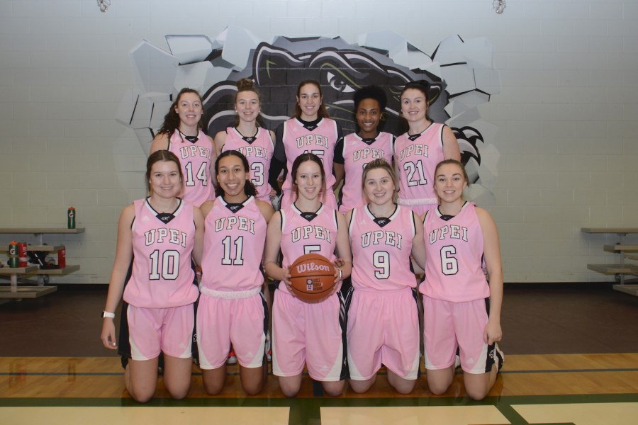 A posed image of ten female basketball players wearing pink jerseys