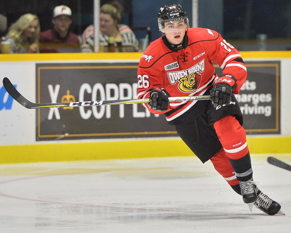 A hockey player in a red and black uniform skates down the ice