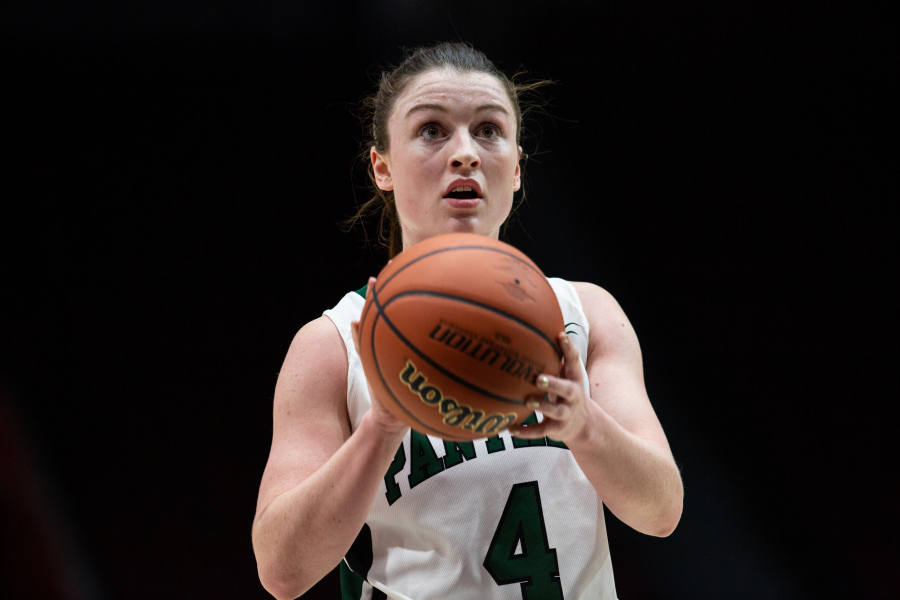 A female basketball player in a green and white Panthers uniform concentrates on a free-throw attempt