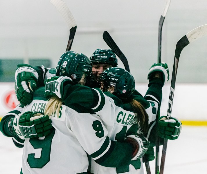 Members of the UPEI Women's Hockey team celebrate a goal with a mid-ice hug