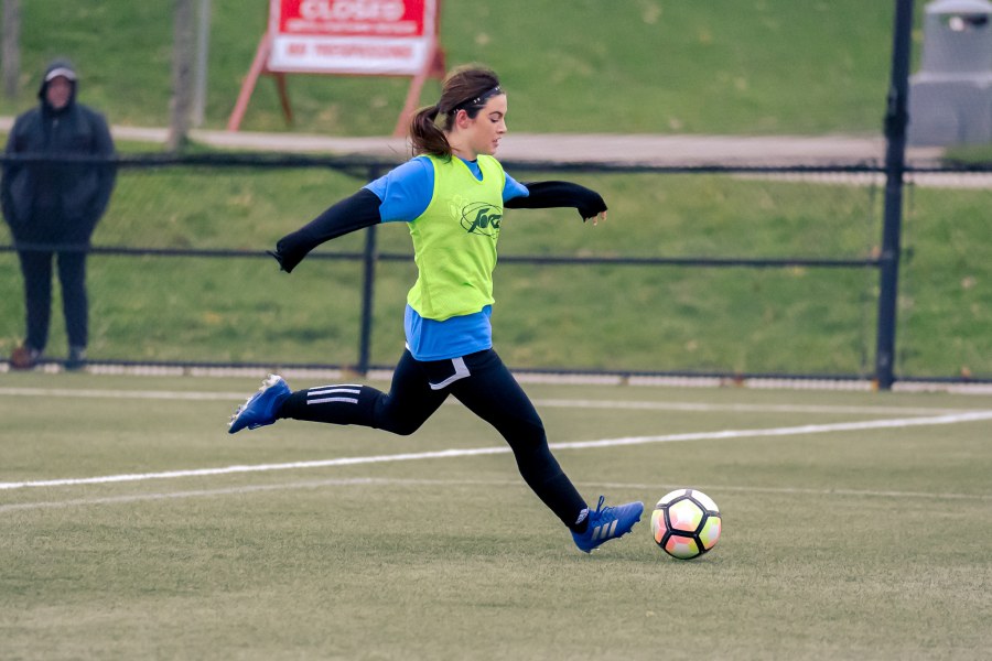 Woman dribbling soccer ball on grass pitch