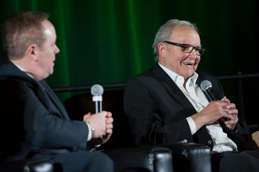 Two men sitting on a stage holding microphones