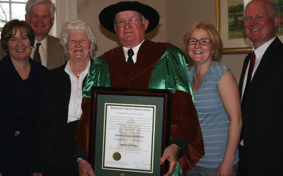 photo of man in academic regalia surrounded by his family