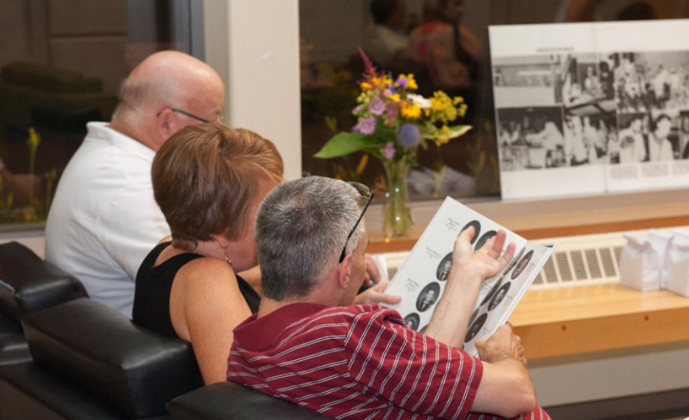 photo of three people looking at yearbooks