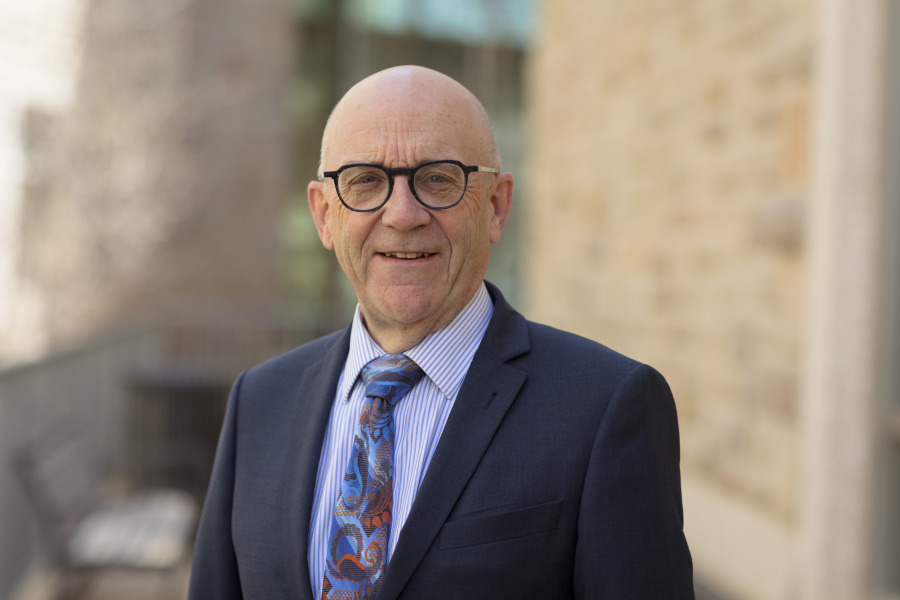 man wearing suit and glasses standing in front of brick wall