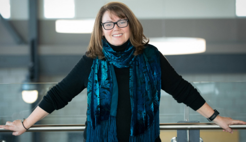 photo of woman wearing glasses leaning against a railing