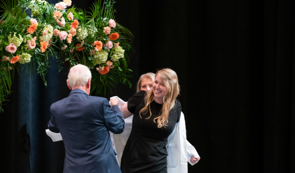 Student receives their white coat at graduation