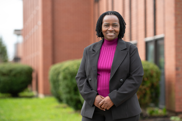 Photo of woman wearing a blazer standing outside a brick building