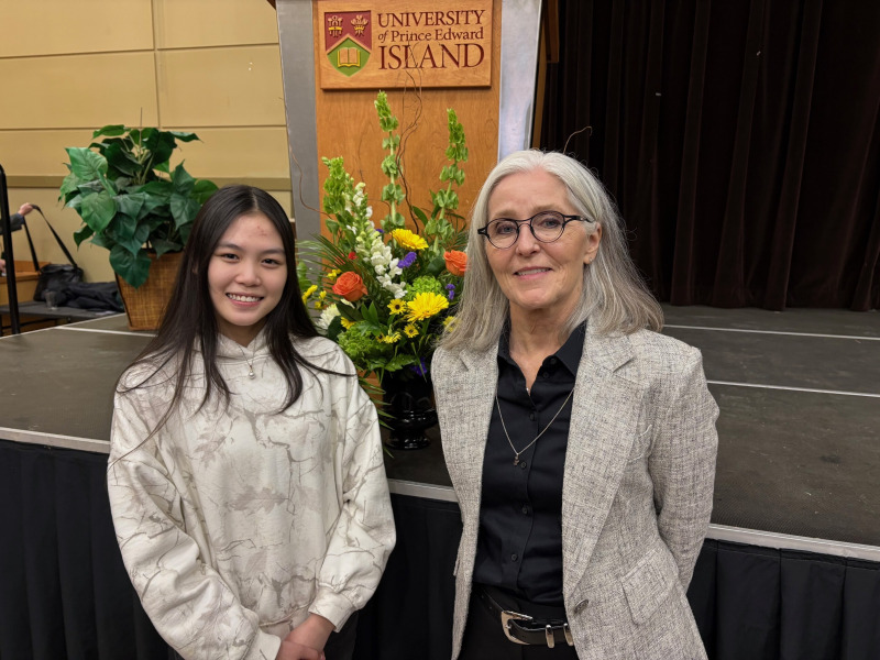 Photo of two women smiling standing in front of a stage and podium