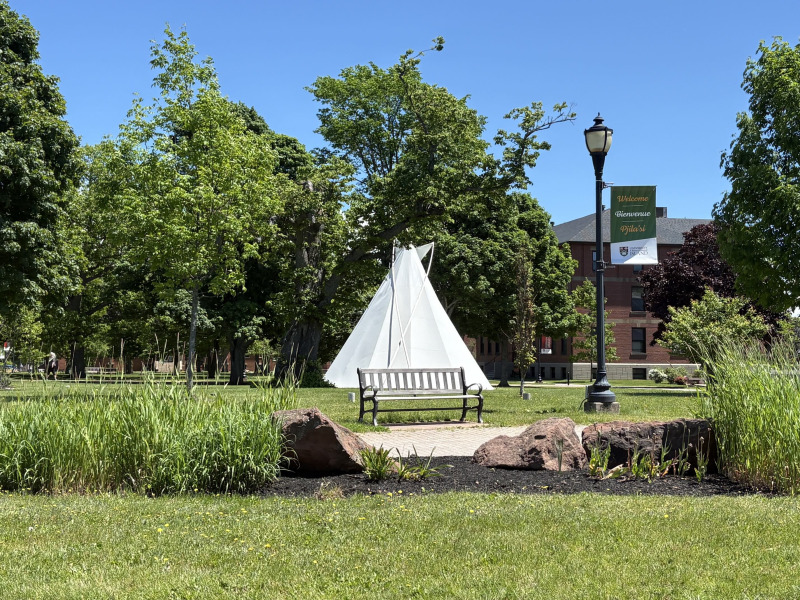photo of tipi and the campus quad with a welcome banner in the foreground