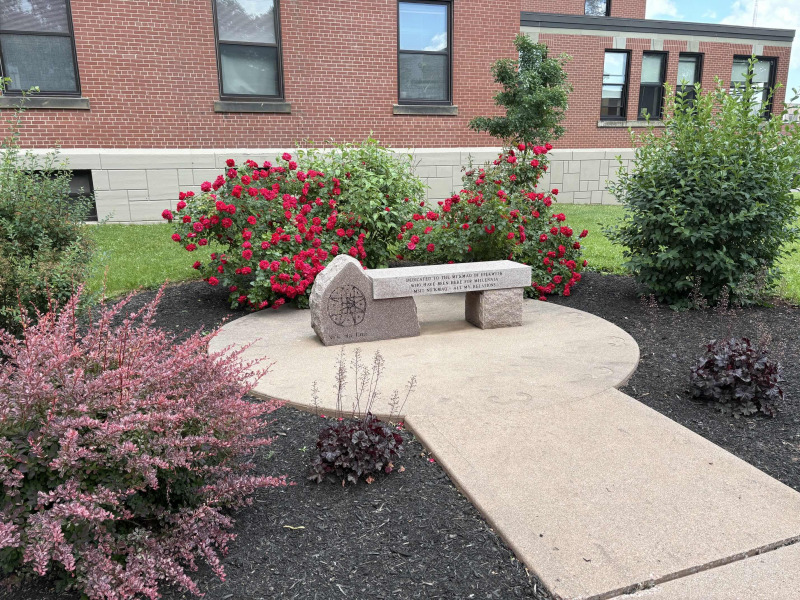 Photo of stone bench surrounded by shrubs in bloom