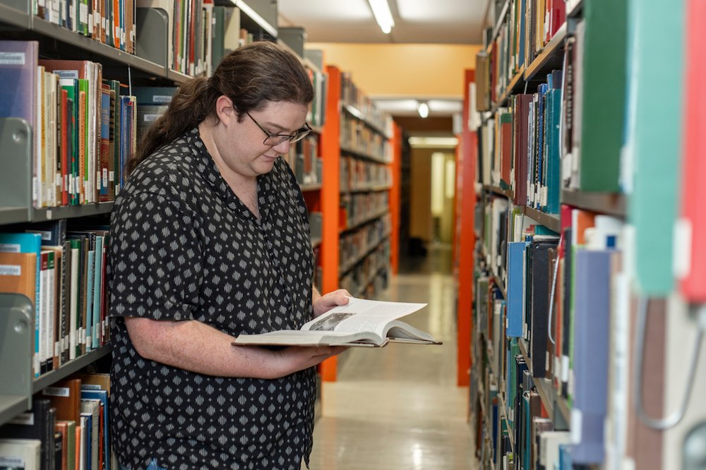UPEI History student Riley Drake in the library book stacks