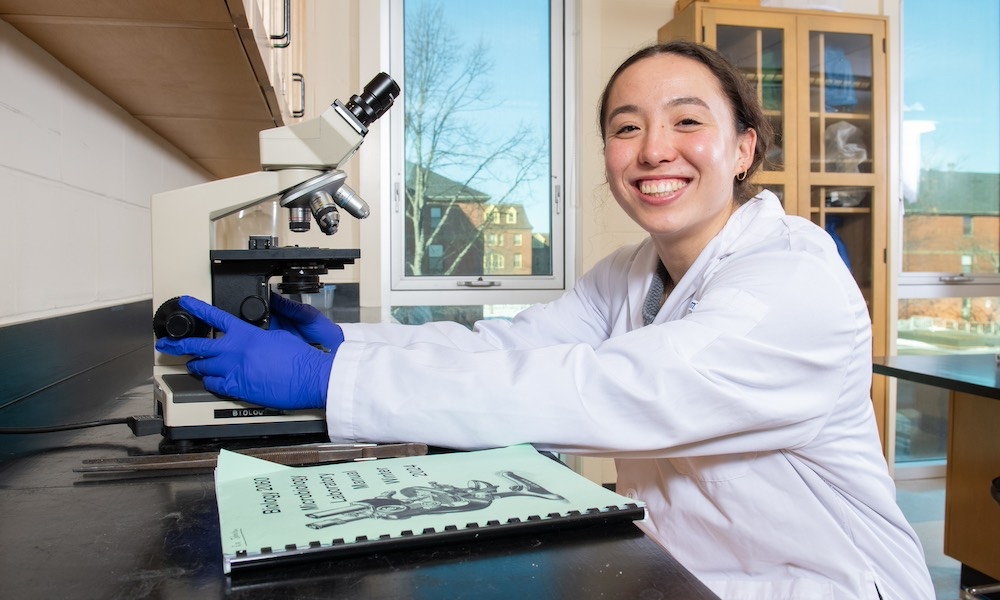 a UPEI biology student in a laboratory using a microscope