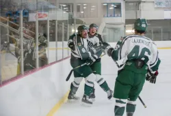 Three hockey players celebrate a goal