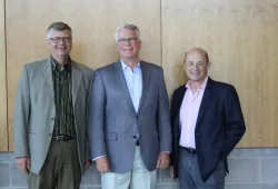 three smiling men in suits