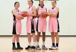 Four female basketball players in pink uniforms