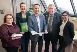 Five smiling people in a library