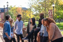 A group of students laughing on a summer day on campus