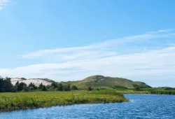 A grassy hill in the background with water in the foreground