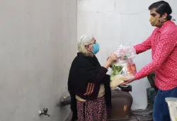 A man hand-delvers a basket of food to an older woman