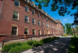 A three story old brick building framed by large trees, recognizable as UPEI's iconic SDU Main Building