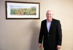 Photo of Dr. Greg Keefe standing by a painting at the Atlantic Veterinary College at UPEI