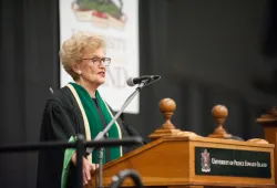 Photo of woman wearing academic dress standing at a podium