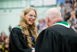 photo of graduate shaking hands with man in gown