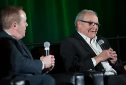 Two men sitting on a stage holding microphones