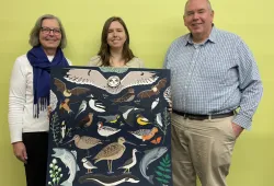 Three people display painting.