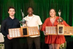 photo of three people holding large trophies