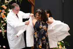 Dr. Alondra Crespo-Rivera (centre) receives her white coat from AVC’s Dr. Patrick Burns (left) and her mother, Sonylma Rivera (right). 
