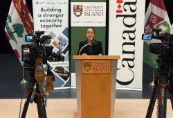Photo of a woman standing at a podium flanked by video cameras