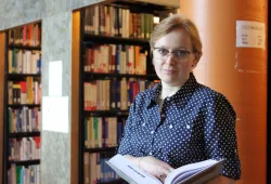 Photo of woman standing in front of book stacks