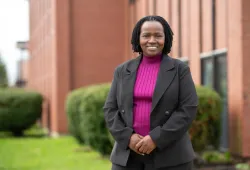 Photo of woman wearing a blazer standing outside a brick building