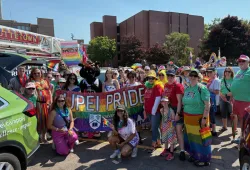 Group of people wearing colourful clothing and carrying Pride