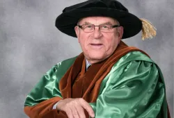 Photo of man wearing glasses and academic regalia