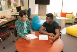 students sit at a desk writing