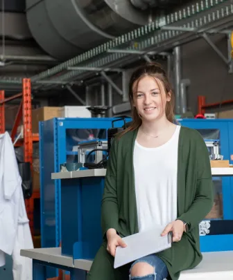 a female engineering student sitting on a desk in a project bay