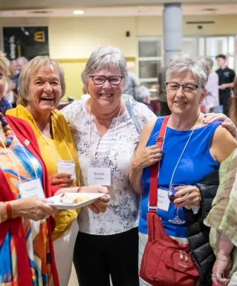 five women smiling for a photo at an alumni function