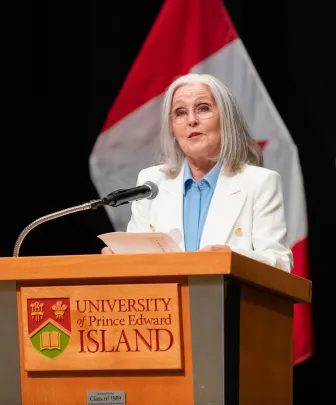 Dr. Wendy Rogers at a podium with flags in the background