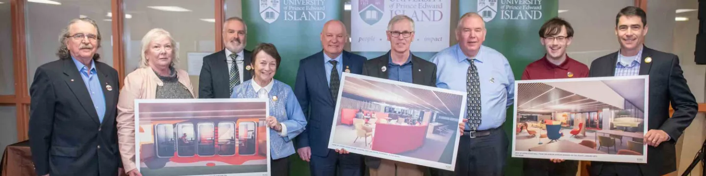 a group of nine people in Robertson Library holding large artist renderings