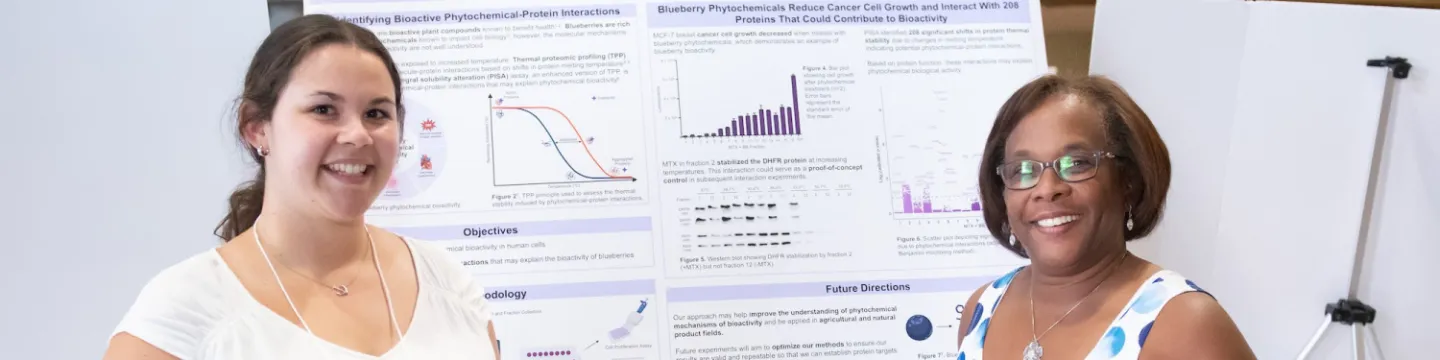 two smiling presenters with a student poster