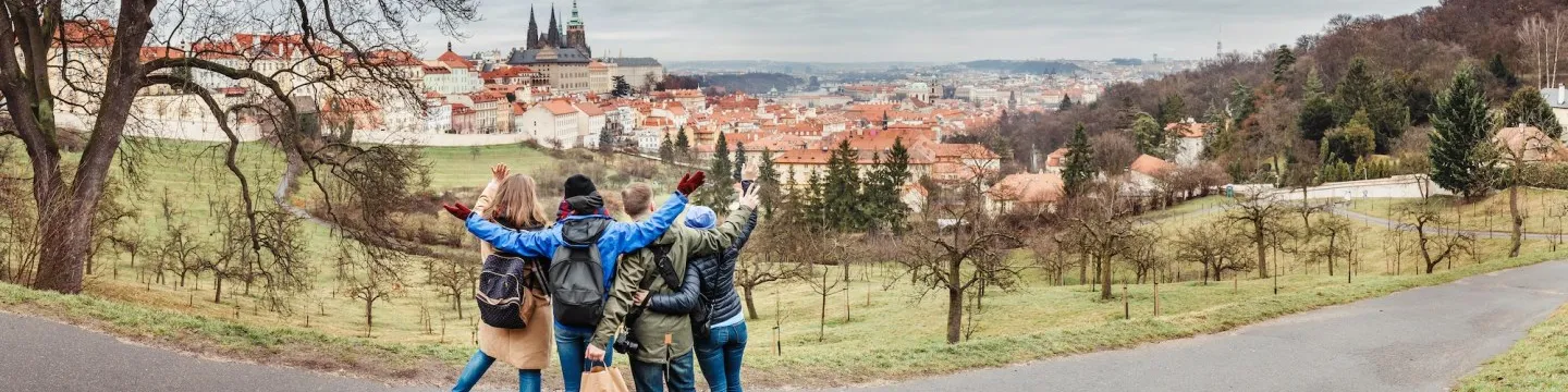 four students standing with their backs to the camera, looking at a european cityscape