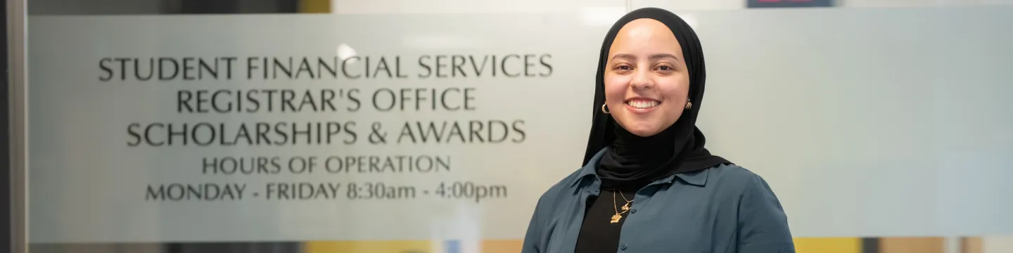 UPEI staff member Fairouz standing outside the UPEI Scholarships, Awards, and Financial Aid Office