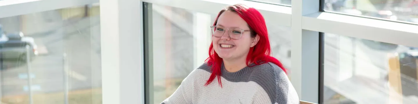 a UPEI student and a laptop computer in the Performing Arts Centre and Residence lounge