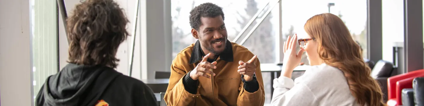 three students talking at a small table